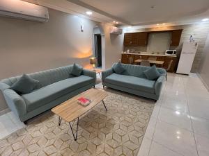 a living room with two blue couches and a table at ليالي الشرقية لشقق المخدومة in Dammam