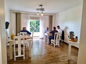 un grupo de personas sentadas en mesas en una habitación en Nimaro Courts, en Entebbe