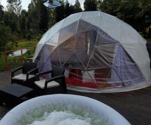 uma tenda cúpula num deque com cadeiras e uma lagoa em Domo -glamping luna em Ráquira