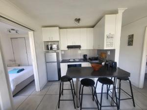 a small kitchen with a table and stools and a bed at Hermanus Beach Club in Hermanus