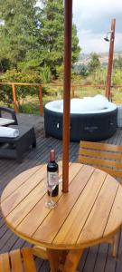 拉基拉的住宿－Domo -glamping luna，甲板上木桌旁的一瓶葡萄酒