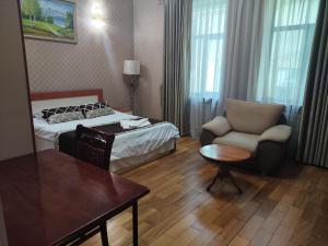 een hotelkamer met een bed, een stoel en een tafel bij ALMOS in Doesjanbe