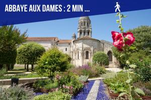 un ancien bâtiment avec une tour d'horloge dans un jardin dans l'établissement La Terrasse - Parking Gratuit - Fibre - RDC - Centre Ville, à Saintes