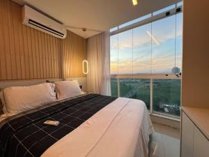 een slaapkamer met een bed en een groot raam bij Ilhas Alto Luxo Praia de Itaparica in Vila Velha