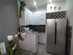 uma cozinha com armários brancos e um frigorífico de aço inoxidável em A vista perfeita em Luanda