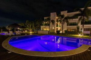 ein Pool in der Nacht mit violetten Lichtern in der Unterkunft Complexo Iberostar - Praia do Forte Bahia - Imóveis de Luxo, de 2 e 3 quartos no melhor local da Praia do Forte in Mata de Sao Joao