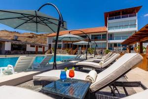 a pool with lounge chairs and a table and an umbrella at Hotel Boutique Caleta Grau in Zorritos