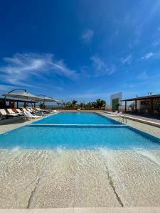 una gran piscina con agua azul y sillas en Hotel Boutique Caleta Grau en Zorritos