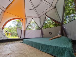 a room with a bed in a tent with a large window at Que Brota Do Chão in Itacaré