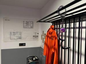 una chaqueta naranja está colgada en una puerta de hierro en 50 nuances de gris - BDSM - Loveroom en Souppes-sur-Loing