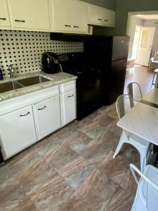 a kitchen with white cabinets and a sink and a table at Cozy two bedroom home near downtown Shawnee in Shawnee