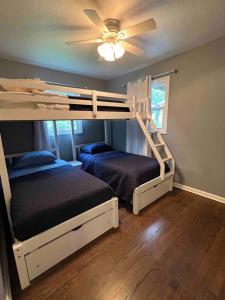 a bedroom with two bunk beds and a ceiling fan at Cozy two bedroom home near downtown Shawnee in Shawnee