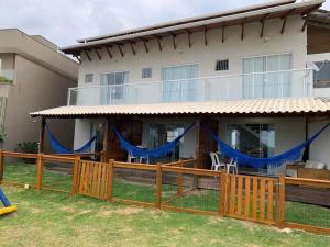 una casa con una valla de madera y cortinas azules en Apartamento frente ao Mar Mariscal 4 pessoas, en Bombinhas