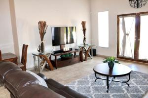 uma sala de estar com um sofá de couro e uma televisão em Beautiful and Comfortable Southwestern Home 1 em Las Cruces