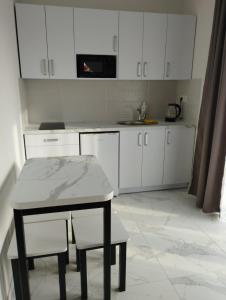 a kitchen with white cabinets and a table and stool at Апарт-готель Перлина Карпат in Skhidnitsa