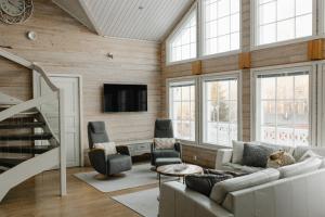 ein Wohnzimmer mit einem Sofa, Stühlen und einem TV in der Unterkunft Arcticmint in Rovaniemi