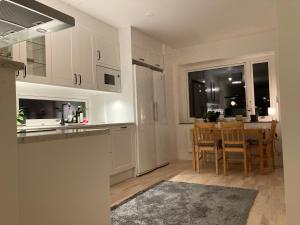 uma cozinha e sala de jantar com armários brancos e uma mesa em Cozy Room em Borås