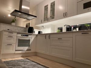 una cocina con armarios blancos y fregadero en Cozy Room en Borås