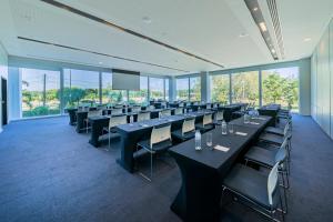 uma sala de conferências com mesas, cadeiras e janelas em Lagune Barra Hotel no Rio de Janeiro