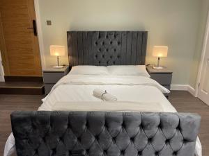 a large bed with a black headboard and two lamps at Cosy Studio Flat with Balcony in Heart of London in London