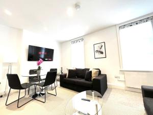 a living room with a couch and a table and chairs at 2 Bedroom Apartment-Oxford Street-Central London in London