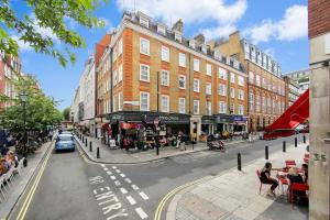 a city street with buildings and people sitting in chairs at 2 Bedroom Apartment-Oxford Street-Central London in London