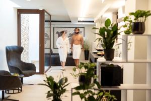 a man and woman walking through a room with plants at Wellness Smart Suites in Bolzano