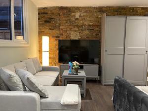 a living room with two couches and a brick wall at Cosy Studio Flat with Balcony in Heart of London in London
