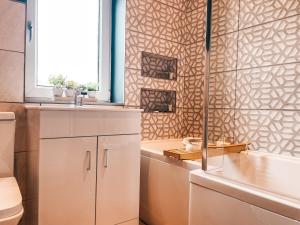 a bathroom with a toilet and a sink and a window at Rosslyn House by Solace Stays in Newport