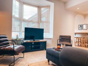 sala de estar con TV y 2 sillas en Rosslyn House by Solace Stays, en Newport