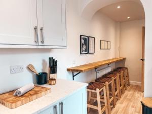 Una cocina con una fila de taburetes debajo de un mostrador. en Rosslyn House by Solace Stays, en Newport 12 fotos más