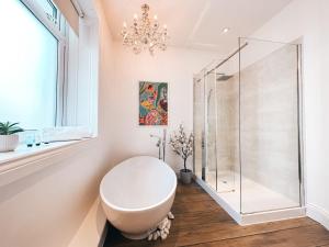 a bathroom with a white tub and a glass shower at Ty Crindau by Solace Stays (Pool Table) in Newport