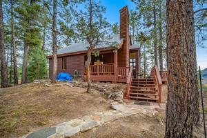 a log cabin in the woods with a large porch and trees at Top of the Mesa in Durango