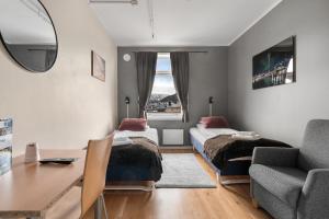 a bedroom with two beds and a desk and a chair at Enter Backpack Hotel in Tromsø