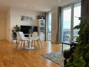 a living room with a table and white chairs at Luxury en-suite room Olympic Village in shared apartment in London