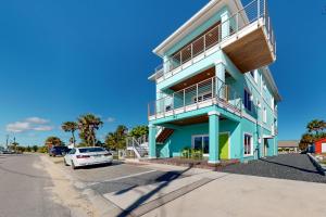 niebieski budynek z samochodem zaparkowanym przed nim w obiekcie Salty Waves 2 w mieście Flagler Beach