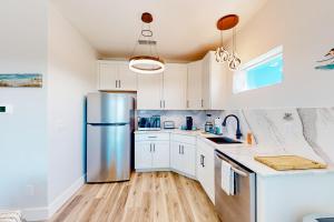 una cucina con mobili bianchi e un frigorifero in acciaio inossidabile di Couple's Getaway, 2nd floor ocean view suite w/ beautiful sunrises, patio, AC a Flagler Beach Altre 17 foto