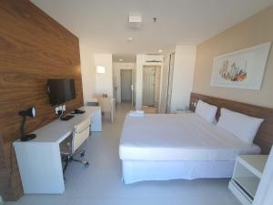 a bedroom with a bed and a desk and a tv at Fusion Express By Rei dos Flats in Brasilia