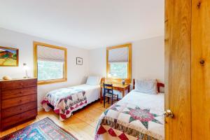 a bedroom with two beds and a desk and a table at Southside at Cobb Nob in Southwest Harbor