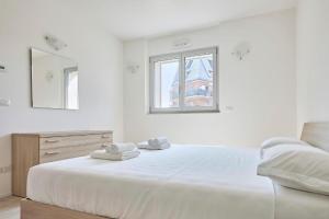 a white bedroom with a large bed and a window at New Twin Flat 1 - Vicino San Siro Stadium e New Palace in Milan