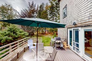 une terrasse avec une table, des chaises et un parasol dans l'établissement Southside at Cobb Nob, à Southwest Harbor