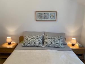 ein Bett mit zwei Kissen und einem Bild an der Wand in der Unterkunft Apartments Zeljko in Lumbarda