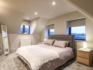 a bedroom with a large bed and two windows at Farley Meadow View in Matlock