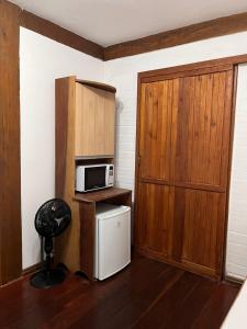 Habitación pequeña con puerta y microondas en Guarda do Embaú, en Guarda do Embaú