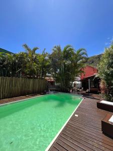 a swimming pool with green water and a wooden deck at Guarda do Embaú in Guarda do Embaú