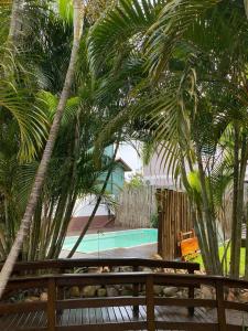un banco de madera junto a una piscina con palmeras en Guarda do Embaú, en Guarda do Embaú