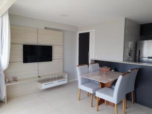 a dining room with a table and chairs and a tv at Studio Iracema 2001 in Fortaleza