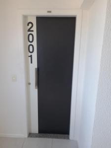 une porte noire dans une chambre blanche avec le numéro dans l'établissement Studio Iracema 2001, à Fortaleza