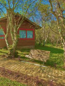 um banco de madeira sentado em frente a uma casa em Pousada & Camping Nativos dos Canyons em Praia Grande