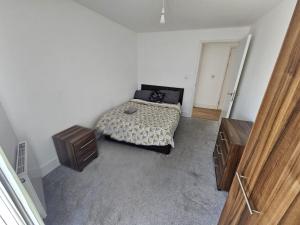 a bedroom with a bed and two wooden cabinets at Hippersley Point, Tilston Bright Square, Abbey Wood, London SE2 9DR, UK in London